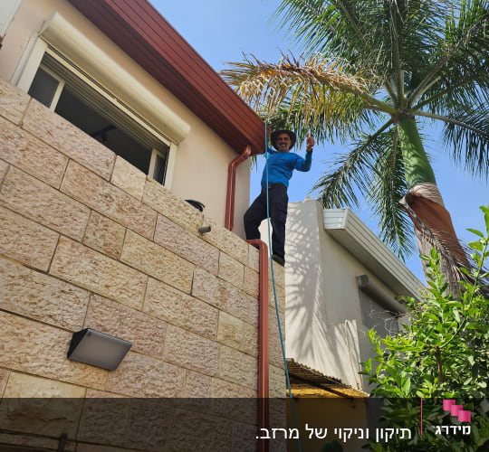 אדם עומד על גג ליד מרזב אדום